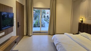 A hotel room with a bed, a TV mounted on the wall, a window with curtains, and a view of the outside.