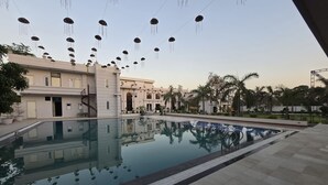 A swimming pool with a reflection of a building and palm trees.