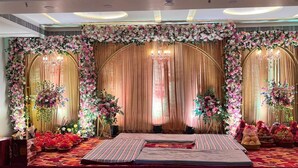 A stage with floral decorations, draped curtains, and a patterned carpet.
