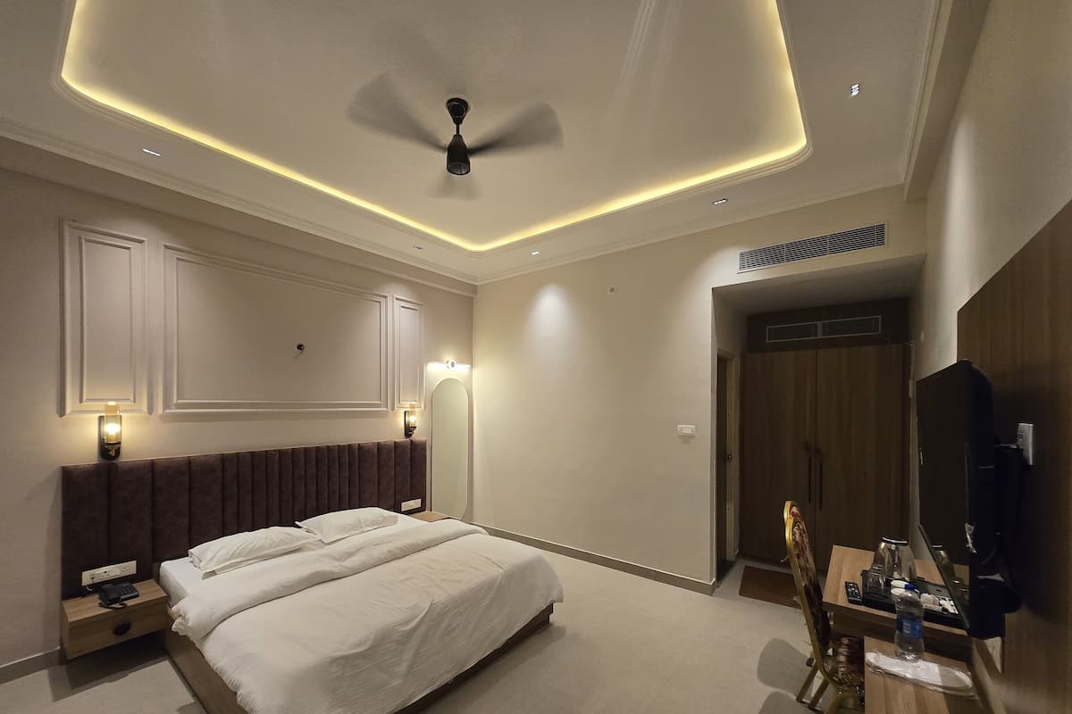 A modern hotel room with a large bed, bedside lamps, a ceiling fan, and a TV.