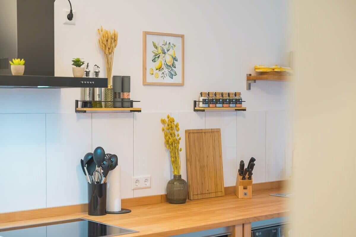 A modern kitchen with a wooden countertop, a black range hood, and various kitchen utensils and appliances.