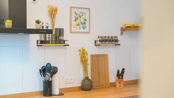 A modern kitchen with a wooden countertop, a black range hood, and various kitchen utensils and appliances.
