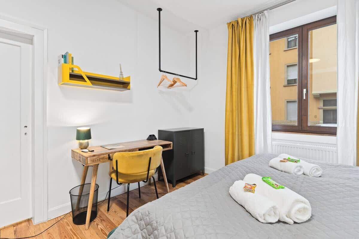 Una camera d'albergo con un letto, una scrivania con una sedia, un armadio e una finestra con tende.