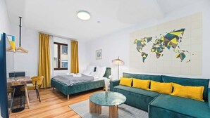 A modern hotel room with a bed, a sofa, a dining area, and a world map on the wall. - Central Karlsruhe Apt: Balcony, Fast WiFi (Karlsruhe)