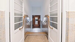 A hallway with white doors, a wooden door at the end, and a carpeted floor. - Central Karlsruhe Apt: Balcony, Fast WiFi (Karlsruhe)