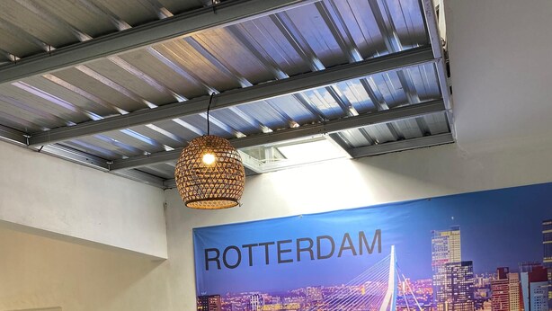 A conference room with a large poster of Rotterdam, a round wooden table, and white chairs. - BADAI HERITAGE VILLA KALIURANG (Pakem)