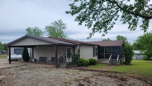 A single-story house with a covered porch, a detached garage, and a small front yard. - 3-bedroom house on Eufaula Lake in delightful Porum (Porum)