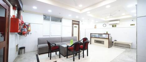 A hotel lobby with a reception desk, seating area, and a fire extinguisher mounted on the wall.
