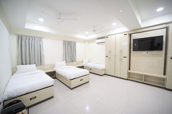 A hotel room with two beds, a TV, a wardrobe, and a ceiling fan. - Hari Haran Prestige (Varanasi)