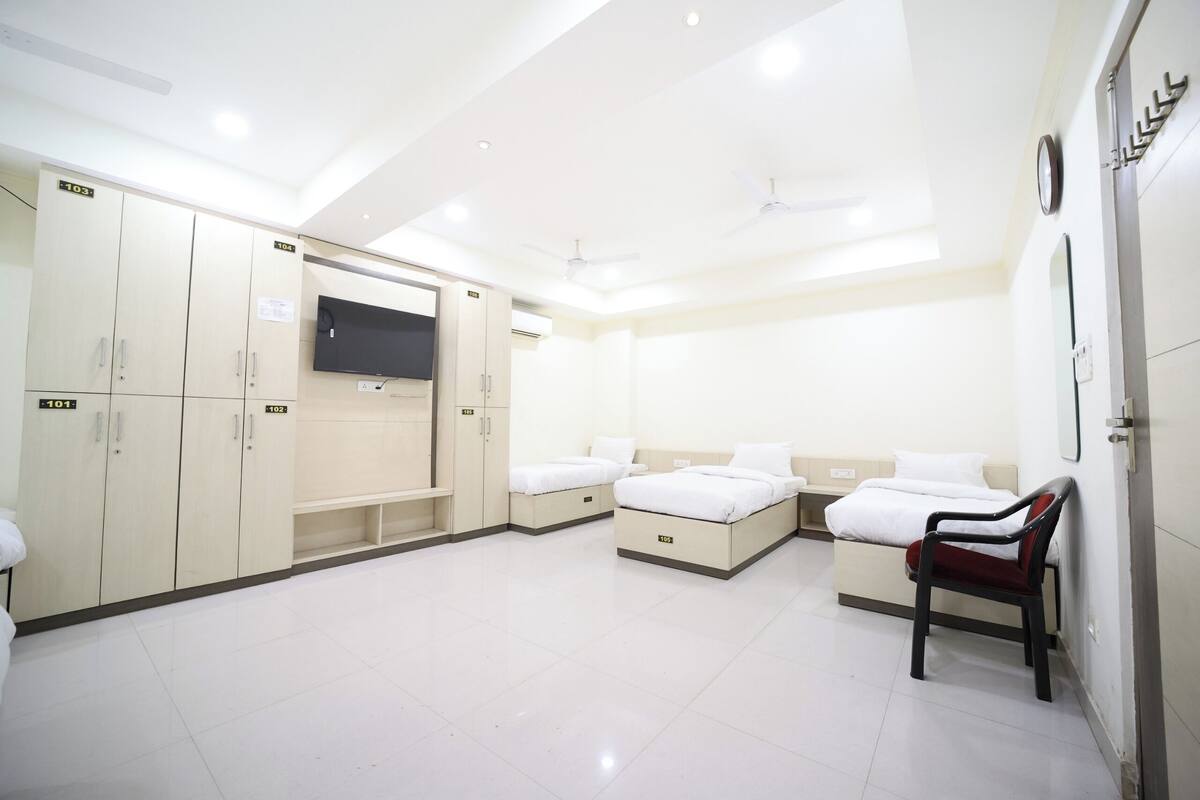 A hotel room with a bed, a desk, a chair, and a wardrobe.