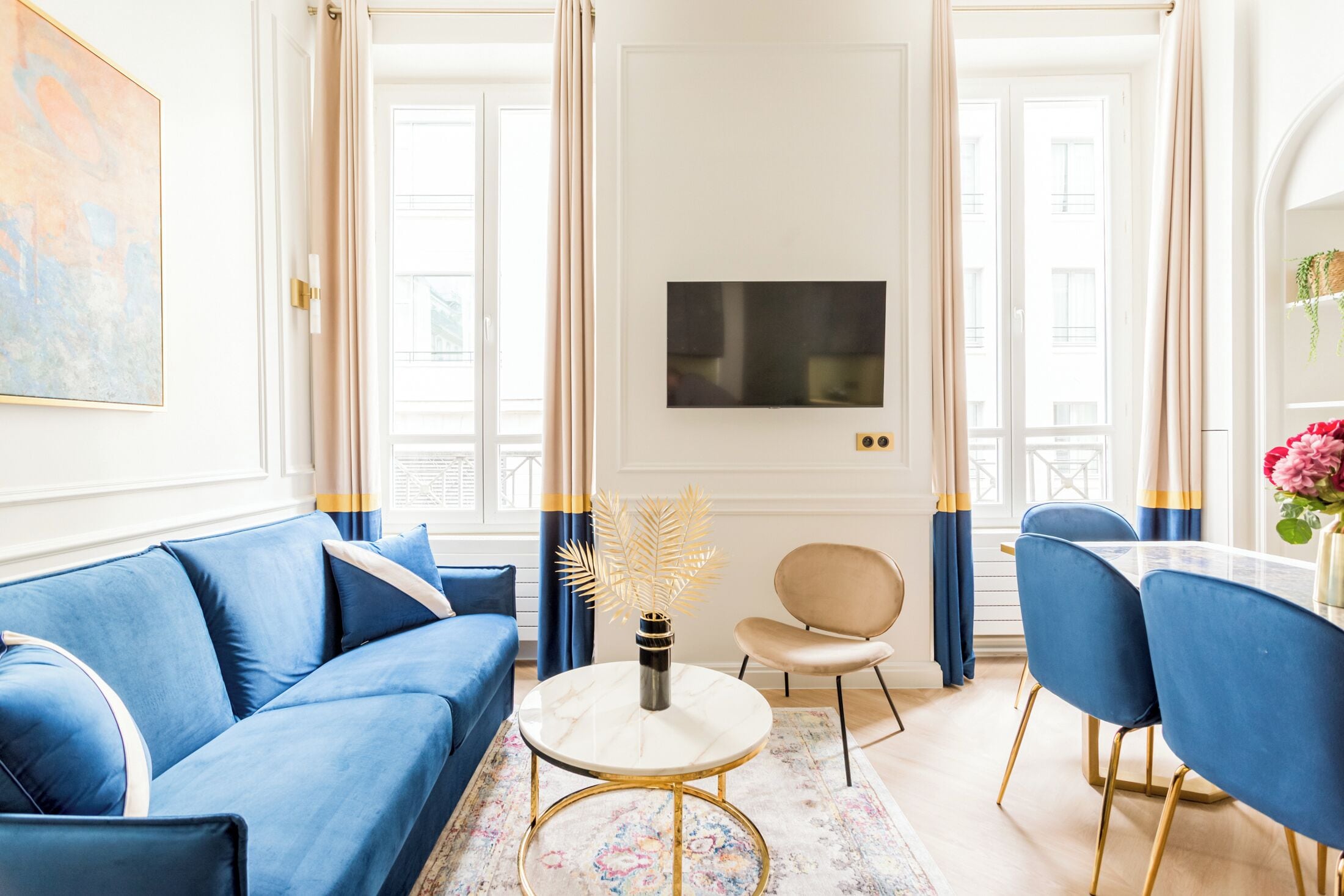 Ein modernes Wohnzimmer mit einem blauen Sofa, einem runden Couchtisch und einem an der Wand befestigten Fernseher.