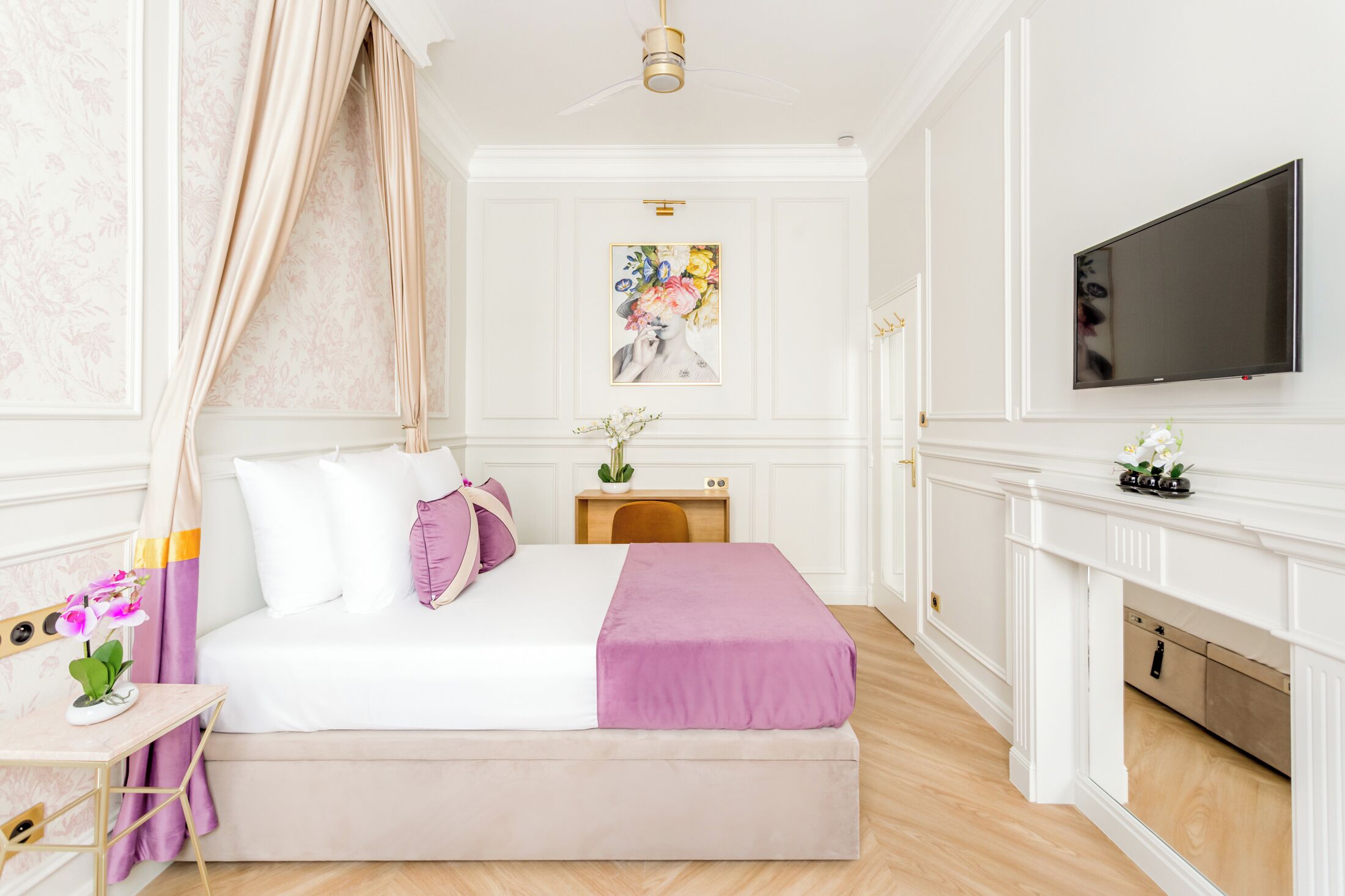 A bedroom with a bed, bedside table, TV, and a fireplace.