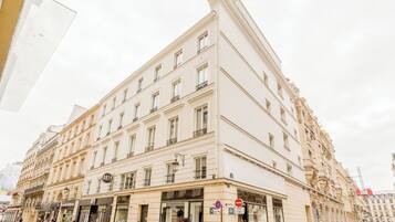 A multi-story building with a classical architectural style, featuring a ground-floor storefront with large windows and a "no entry" sign.