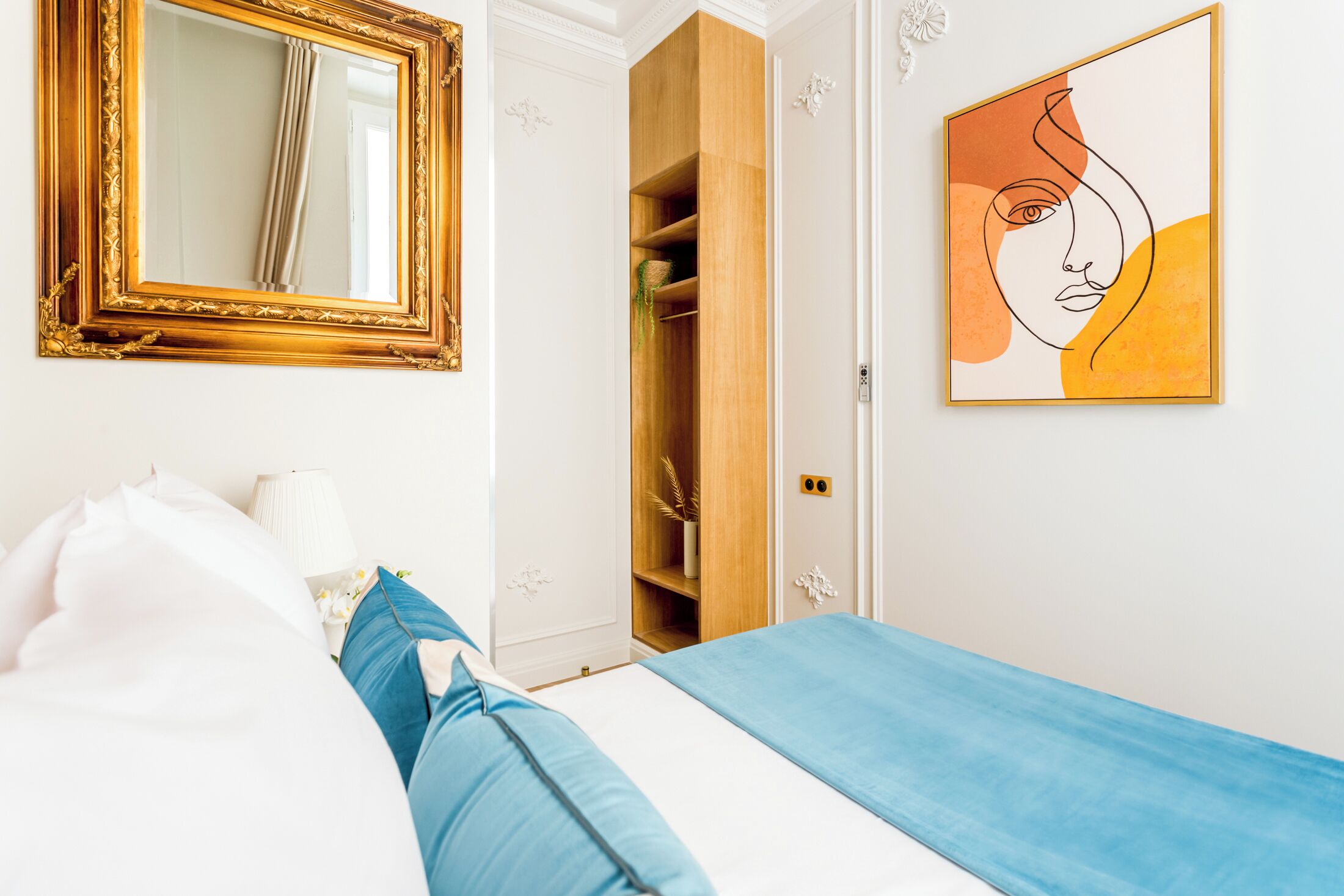 A bedroom with a bed, a wardrobe, a mirror, and a painting.