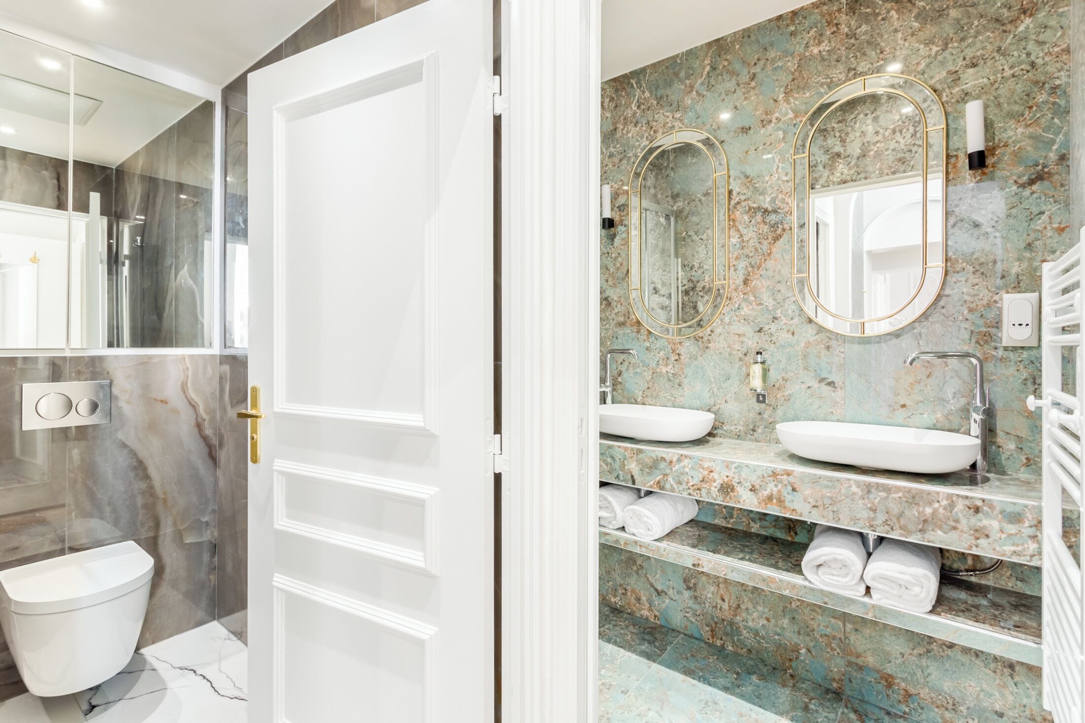 Un baño moderno con tocador de mármol, lavamanos dobles y un inodoro.