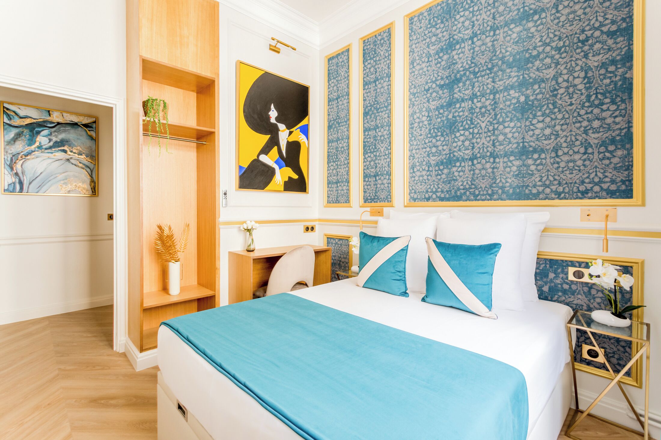 A modern hotel room with a large bed, a desk, and a wardrobe.