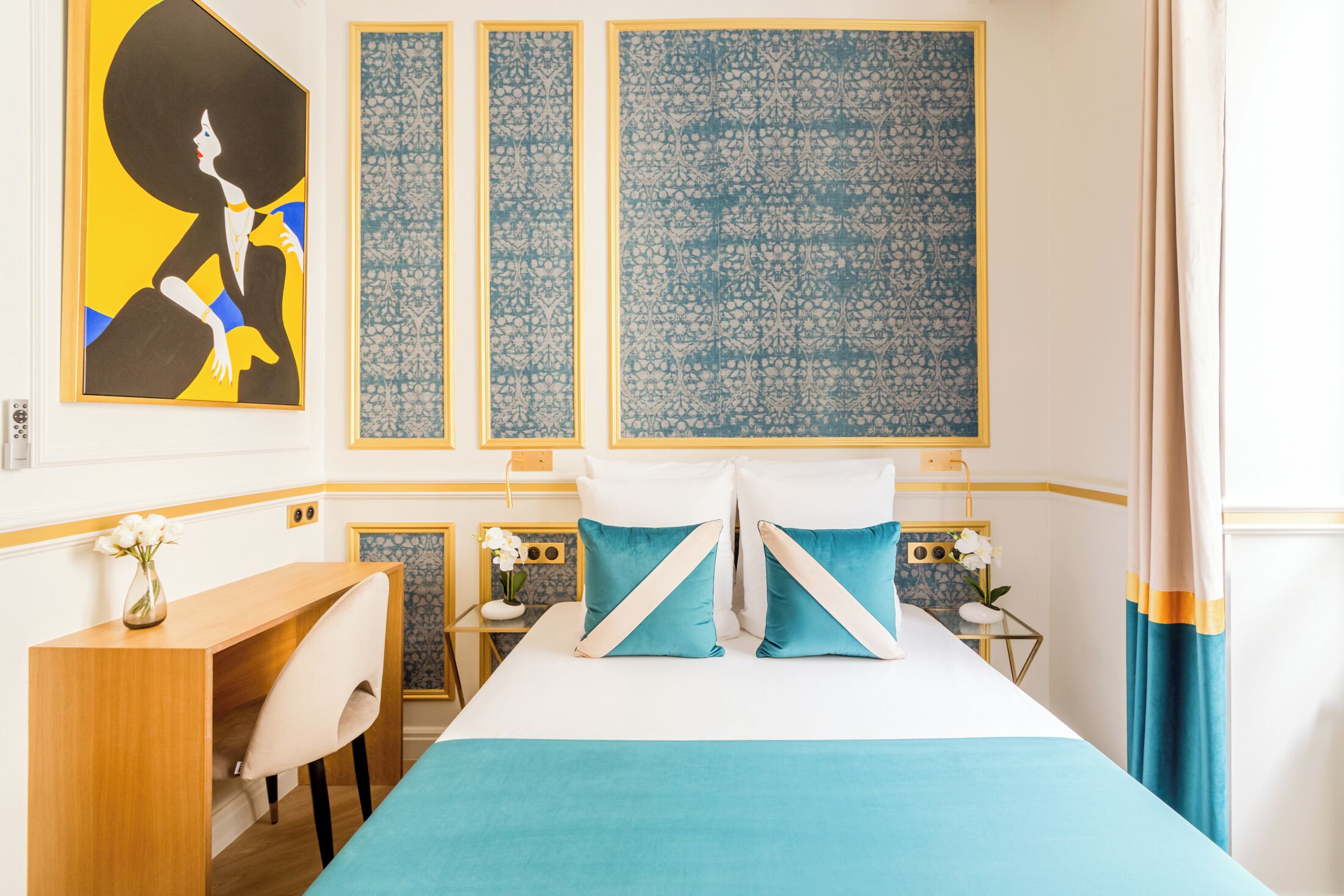 A hotel room with a bed, a desk, and a chair. There are three wall panels with intricate patterns.