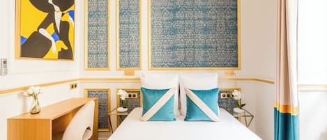 A hotel room with a bed, a desk, and a chair. There are three wall panels with intricate patterns.