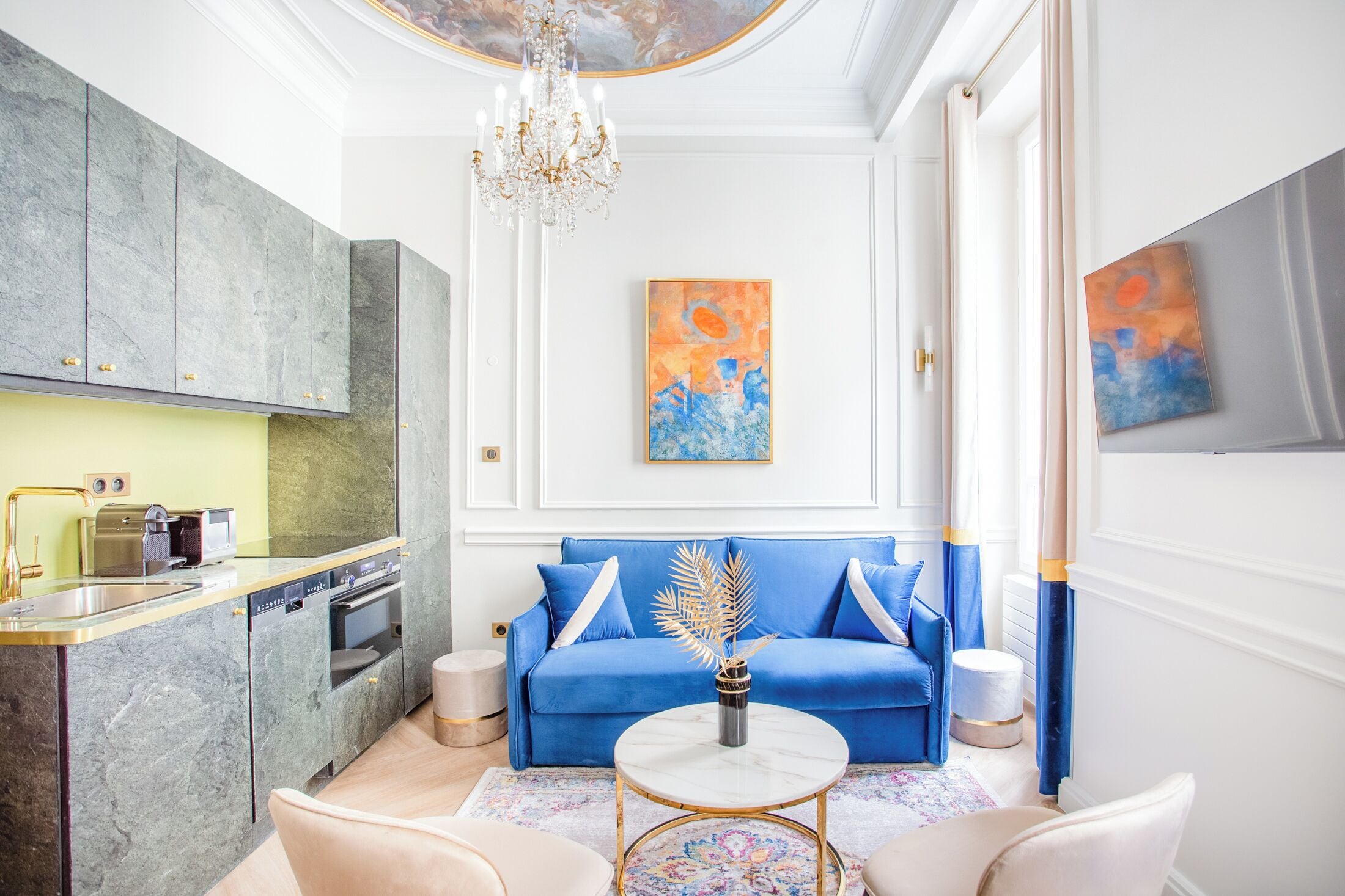 Una sala de estar moderna con un sofá azul, una mesa de centro de mármol y una araña.