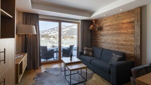 Uma sala de estar moderna com sofá, mesa de centro e vista para uma paisagem nevada através de amplas janelas.