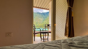 Una habitación con cama, una silla y vistas a un balcón con mesa y sillas.