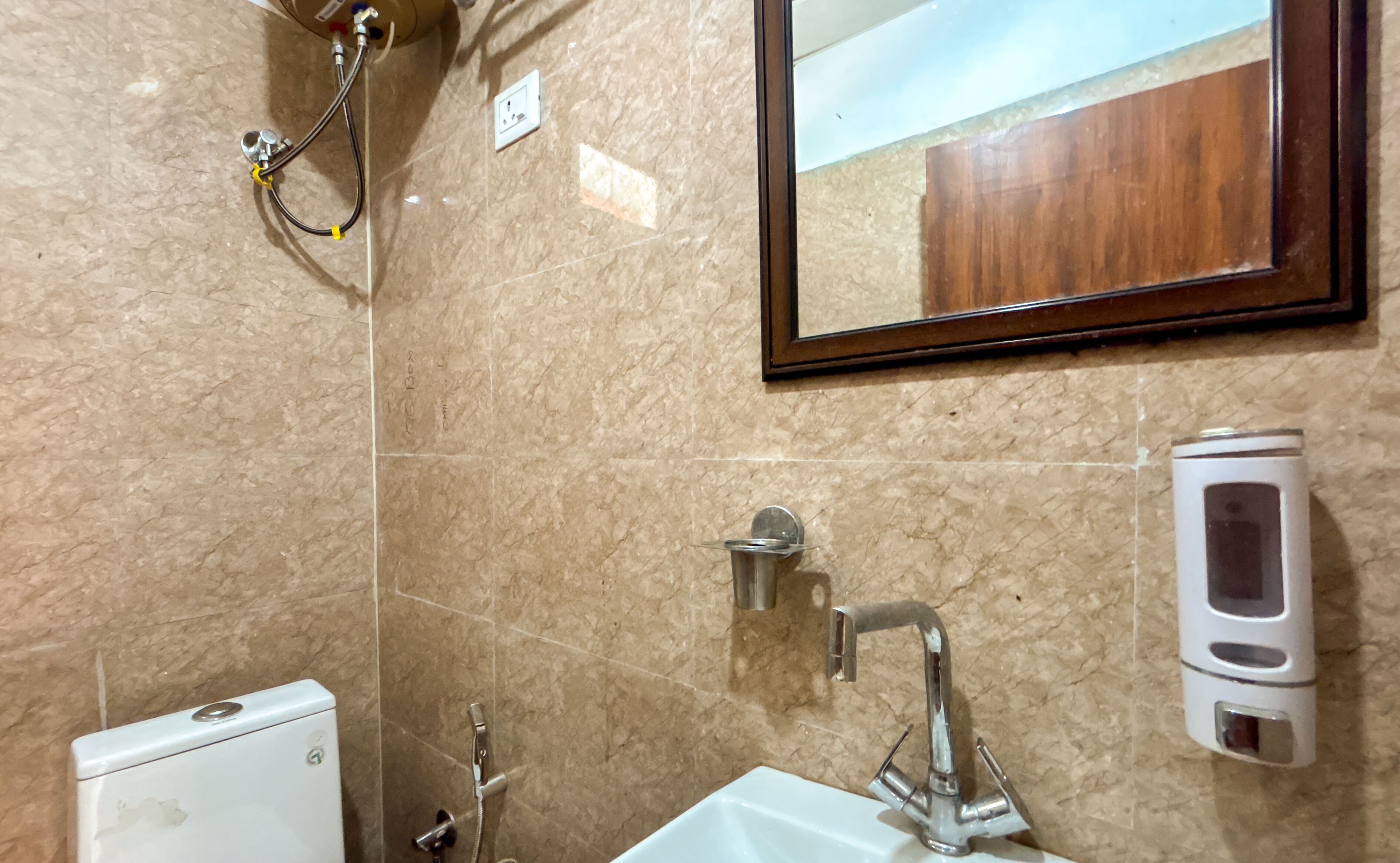 A bathroom with a white toilet, a sink with a mirror, and a shower with a handheld showerhead.