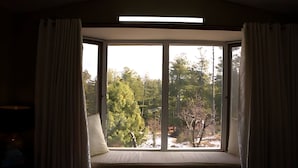 A room with a large window, a bed, and a bedside table. - Alpine Luxe Villa (Murree)
