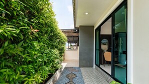 A corridor with a tiled floor, a glass door, and a view of a patio area.