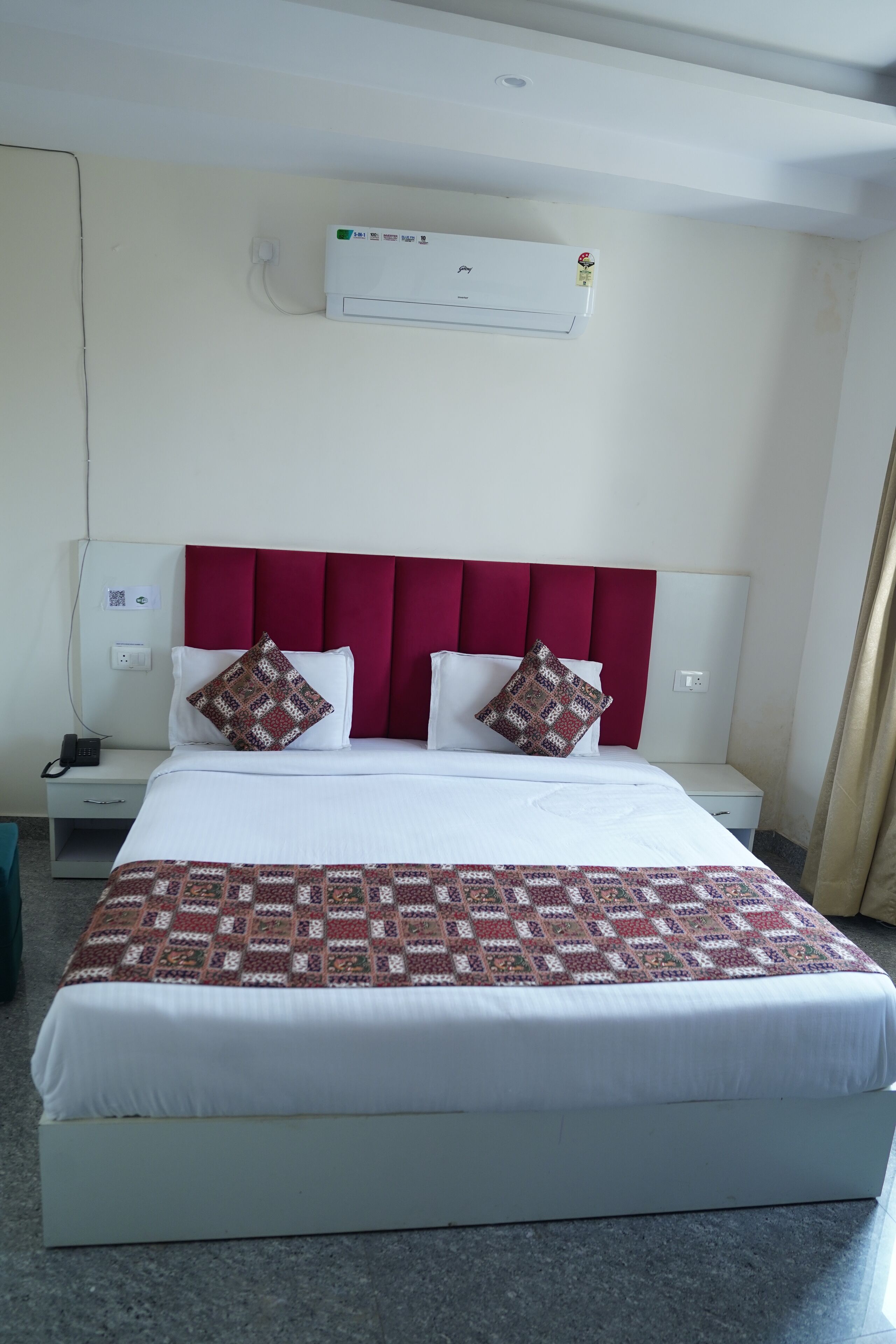 A neatly made bed with a patterned blanket, a red headboard, and two decorative pillows.