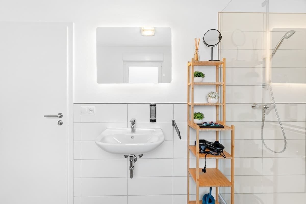 A modern bathroom with a white sink, a mirror, and a shower.