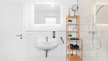A modern bathroom with a white sink, a mirror, and a shower.
