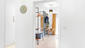 Et moderne interiør med et synligt ur, et spiseområde med bord og stole, samt en hængende lampe.