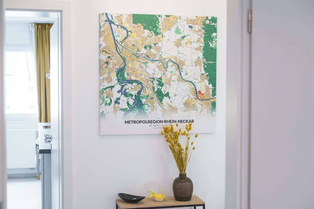 Eine Karte der Metropolregion Rhein-Neckar an einer Wand, ein Tisch mit einer Vase voller gelber Blumen und eine schwarze Schale.