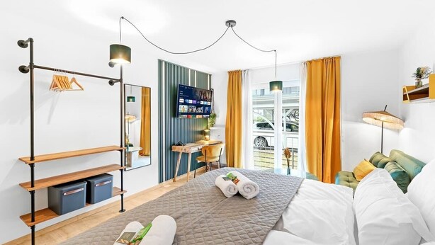 Et moderne hotelværelse med seng, skrivebord, fjernsyn og udsigt ud