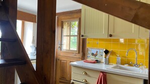 A kitchen with wooden cabinets, a yellow tiled backsplash, and a stainless steel sink.