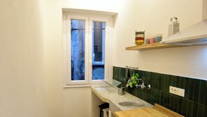 Eine kleine Küche mit Holzboden, einem Fenster, einer Spüle und einem Herd.