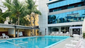 Una piscina amb gandules, un edifici amb un rètol que diu 'MOTEL' i palmeres.