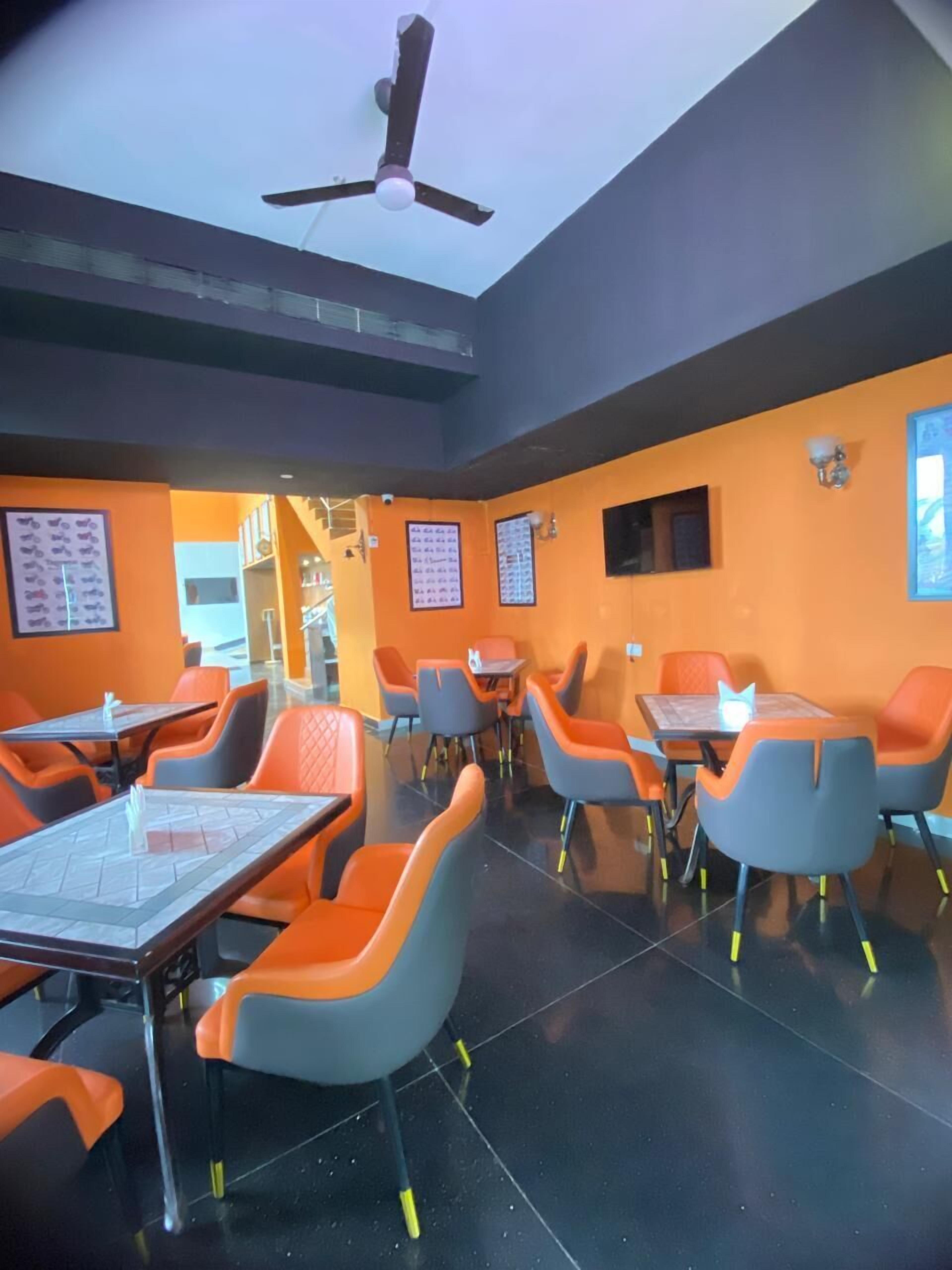 A restaurant with orange and grey chairs, tables, a ceiling fan, and tiled floors.