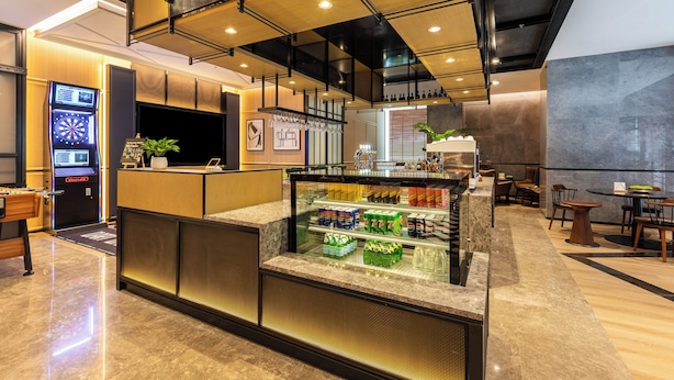 A modern cafe with a counter, seating area, and a display case with snacks. - Beijing Chengying Hotel - Sanlitun Taikoo Li (Beijing)