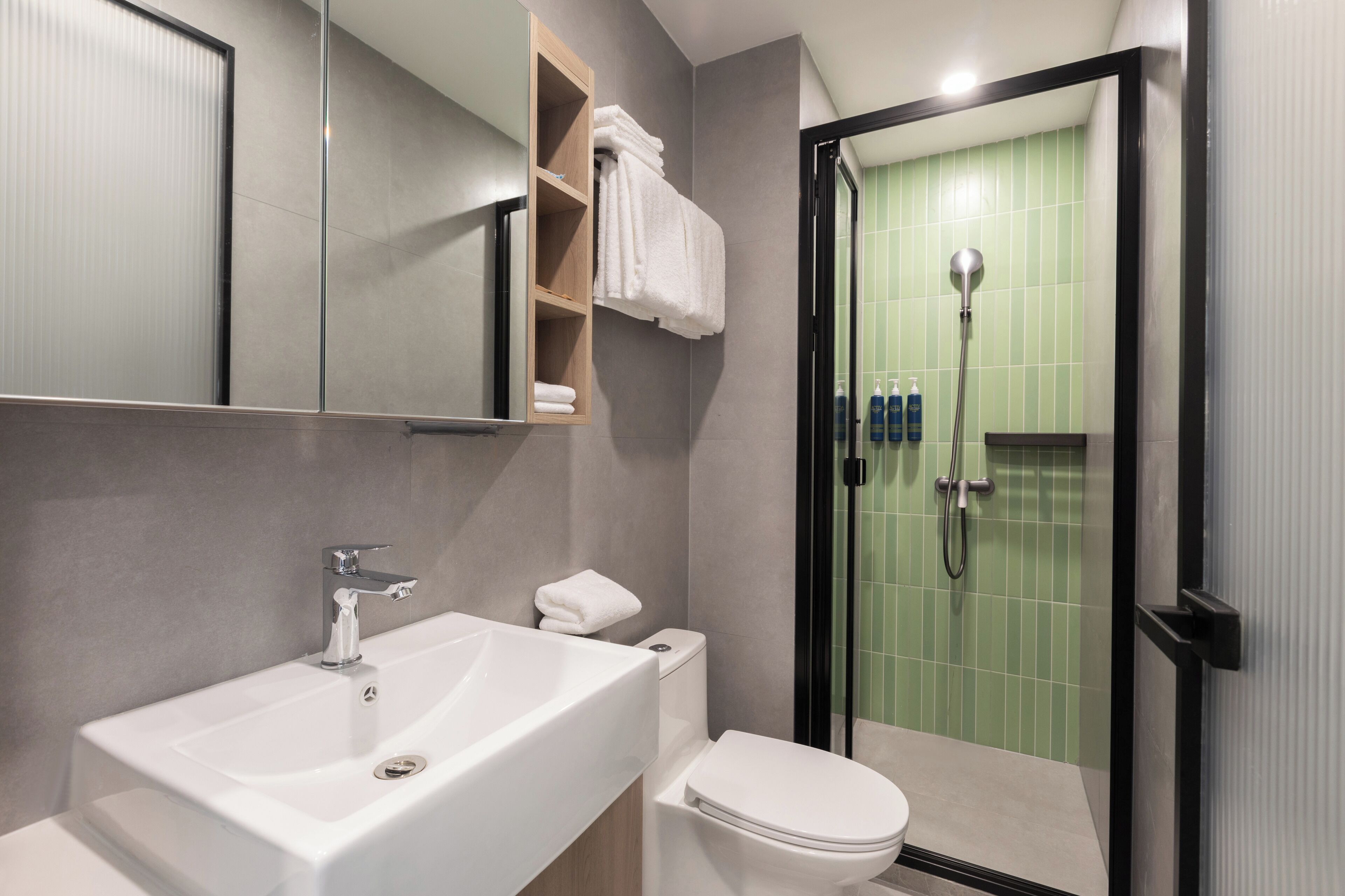 A modern bathroom with a white sink, toilet, and glass-enclosed shower.
