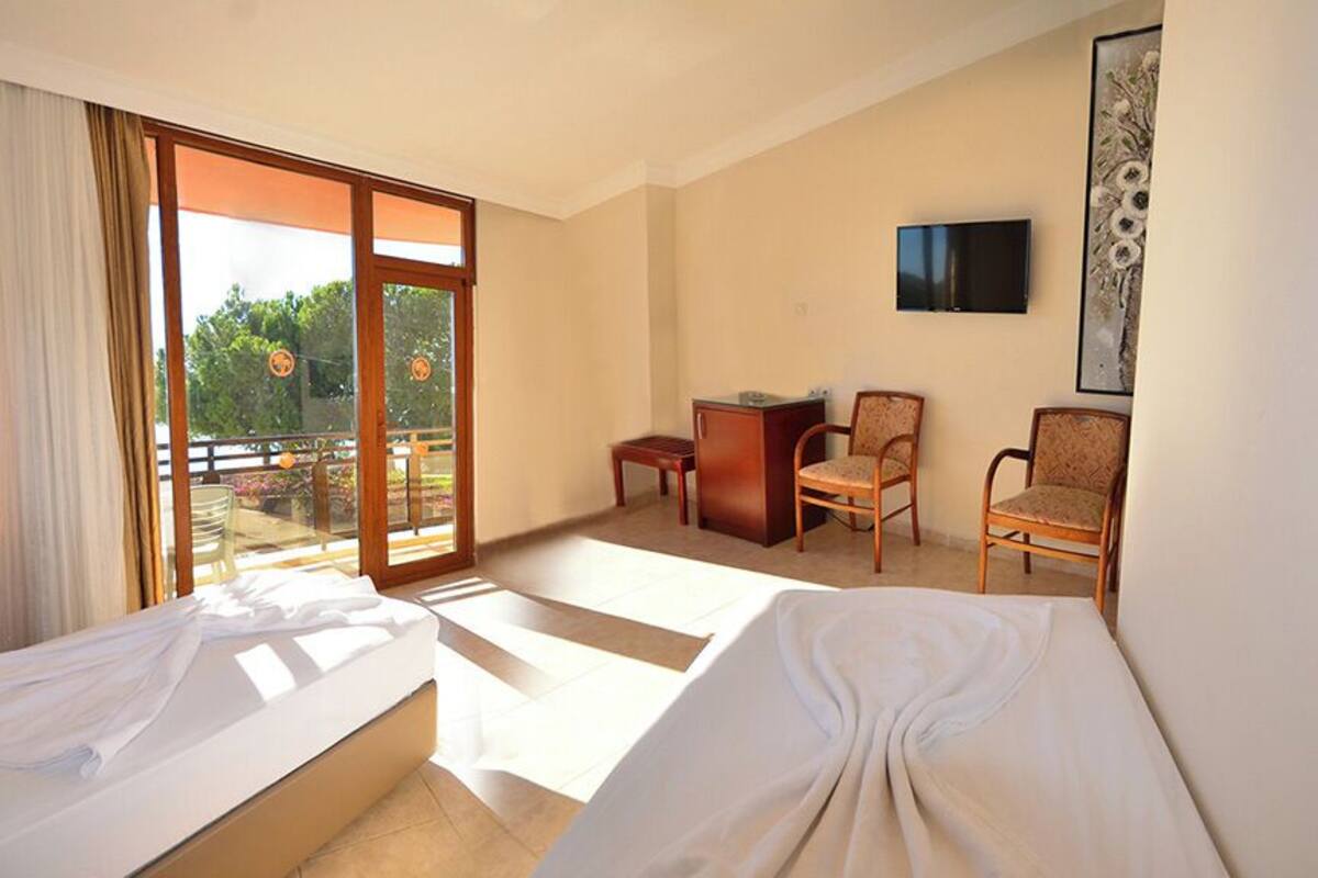 A hotel room with two beds, a TV, a desk, and a chair.