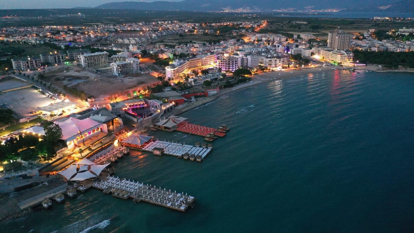 Vista aérea de una ciudad costera con un puerto deportivo, edificios y una zona de playa.