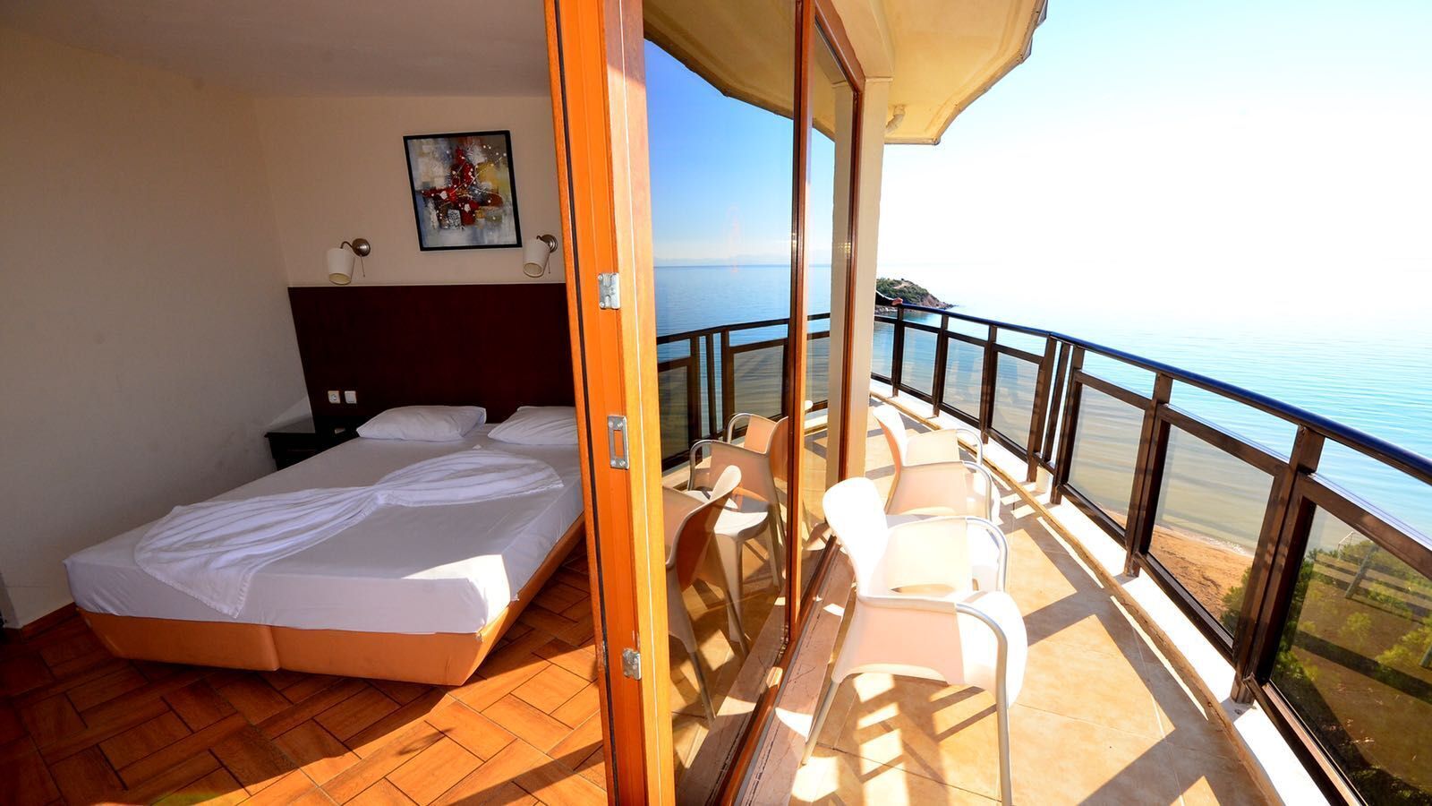 Een balkon met een bed, stoelen en uitzicht op zee.