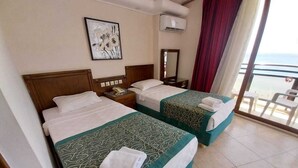 Habitación de hotel con dos camas, un balcón con vistas y un cuadro en la pared.