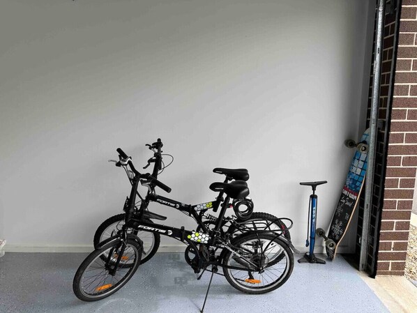 Una bicicleta estacionada adentro, un monopatín apoyado en una pared y un scooter al fondo.