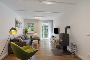Una sala de estar moderna con un sofá, un sillón verde, un televisor, una chimenea y una planta.