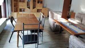 Et spiseområde med et træbord og stole, en sofa og et skab med hylder.