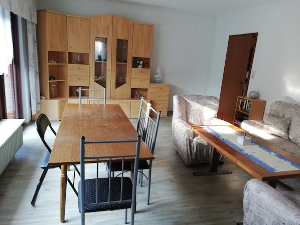Un coin repas comprenant une table et des chaises en bois, un canapé et un meuble avec des étagères.