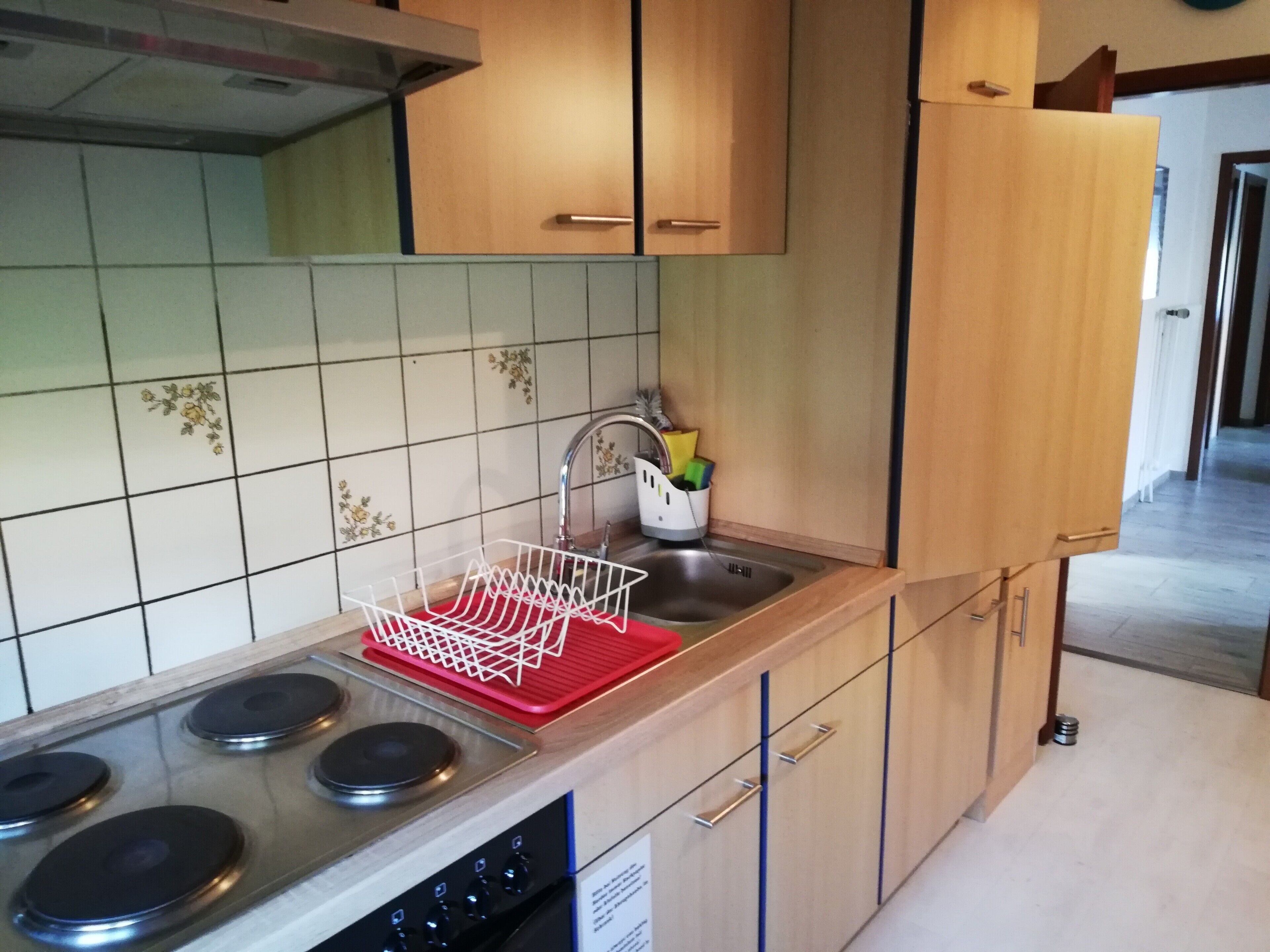 Una cocina moderna con estufa de acero inoxidable, un lavamanos con escurreplatos y armarios de madera.