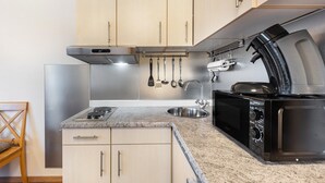 A compact kitchen with a stainless steel refrigerator, a microwave, and a stove.